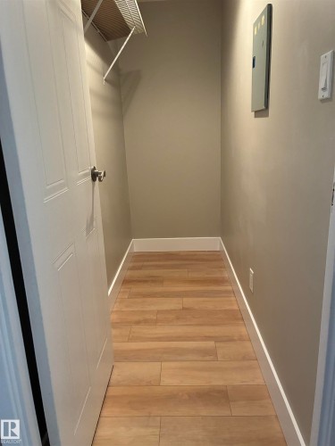 Walk-in closet featuring wood-finish flooring, neutral wall tones, and a wire shelving system - #503 11211 85 St Nw, Edmonton, AB 