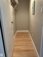 Walk-in closet featuring wood-finish flooring, neutral wall tones, and a wire shelving system - 
