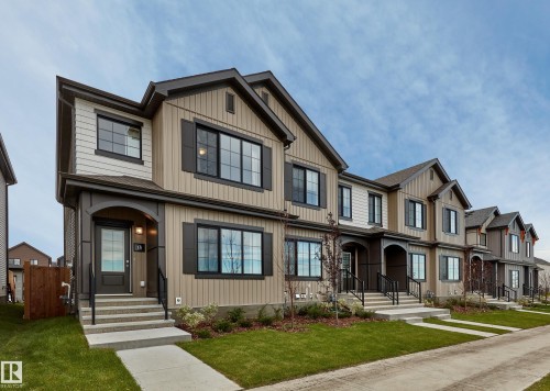 Townhome exterior with a covered entry, dark framed windows, decorative shutters, and a concrete pathway leading to the front door - 129 Chelles Wynd, St. Albert, AB 