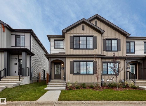 Multi-level facade with vertical and horizontal siding, dark-trimmed windows, decorative shutters, and a covered entry with steps - 129 Chelles Wynd, St. Albert, AB 