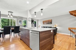 Kitchen island with dark wood-finish cabinetry, a white countertop, and an integrated stainless steel dishwasher - 
