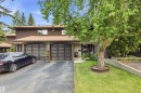Brown vertical siding exterior with dual arched garage doors - 141 Hearthstone Nw, Edmonton, AB  - Outdoor 