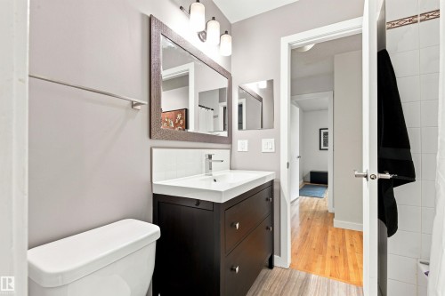 Bathroom featuring a dark wood-finish vanity with a white integrated sink, chrome faucet, and a large framed mirror - 141 Hearthstone Nw, Edmonton, AB - Indoor Photo Showing Bathroom