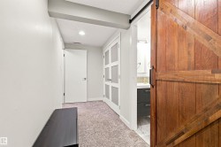 Solid wood barn door with black hardware, leading to a bathroom featuring a modern vanity with dark cabinetry, a vessel sink, and a light-colored countertop - 