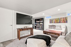 Recreation room featuring recessed lighting, two transom windows, light-colored carpeting, a built-in shelving unit, and a mounted television - 