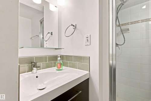 Contemporary bathroom featuring a dark wood-finish vanity with an integrated white sink, chrome faucet, and a subway tile backsplash - 141 Hearthstone Nw, Edmonton, AB - Indoor Photo Showing Bathroom