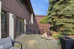 Expansive wood deck with mature evergreen landscaping, featuring a privacy fence and direct access to interior living spaces via sliding glass doors - 