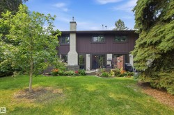 Rear exterior featuring a brown facade with upper-level windows, a stone-clad chimney, and a ground-level patio - 