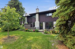 Spacious backyard featuring a manicured lawn, established landscaping, and mature trees - 