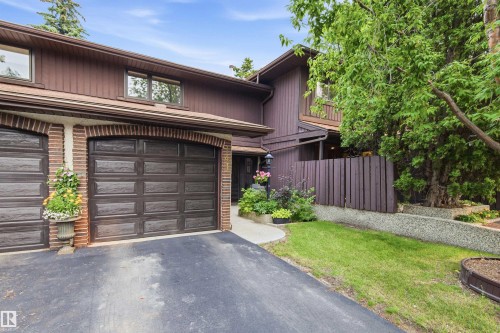 Brown exterior with vertical siding, brick accents, arched garage doors, and mature trees - 141 Hearthstone Nw, Edmonton, AB - Outdoor