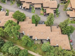 Townhome community featuring multi-level rooflines, individual patios, mature landscaping, and paved pathways - 