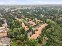 Expansive residential development featuring multiple units with terracotta-style roofs, surrounded by mature trees - 