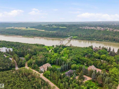 Aerial perspective showcasing a broad river, extensive natural landscapes, a suspension bridge, and residential properties nestled among dense trees - 141 Hearthstone Nw, Edmonton, AB - Outdoor With View