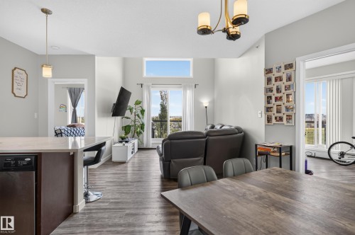 Open-concept living area featuring wood-finish flooring and a vaulted ceiling with a transom window - #411 304 Ambleside Link Li Sw, Edmonton, AB 