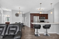 Kitchen with dark wood cabinetry, stainless steel appliances, and a light-toned countertop with breakfast bar seating - 