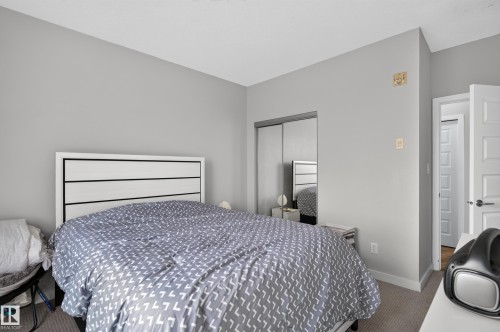 Carpeted flooring with light gray walls, white trim, and a mirrored closet door - #411 304 Ambleside Link Li Sw, Edmonton, AB 