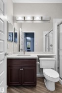 Dark wood-finish vanity with a light-toned countertop, large wall-mounted mirror, brushed nickel faucet, and wood-finish flooring - 