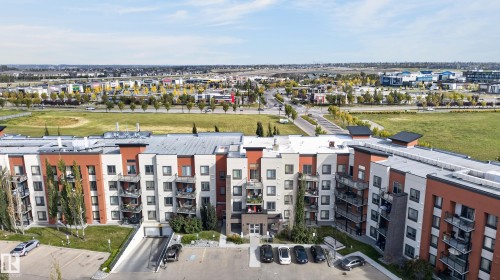 Multi-story residential building with various exterior finishes, multiple balconies, and an underground parking entrance - #411 304 Ambleside Link Li Sw, Edmonton, AB 