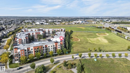 Residential apartment building featuring a contemporary facade with red brick and light-colored siding, individual balconies, and a flat roofline - #411 304 Ambleside Link Li Sw, Edmonton, AB 