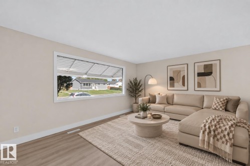Spacious room featuring wood-finish flooring, light-toned walls, and a large picture window - 13511 114 Street Nw, Edmonton, AB 