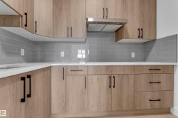 Light wood-finish cabinetry with matte black hardware, white countertops, and a gray subway tile backsplash - 