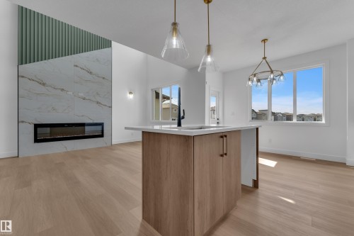 Wood-finish flooring throughout, featuring a kitchen island with light-toned cabinetry and a white countertop - 4212 63 Street, Beaumont, AB 