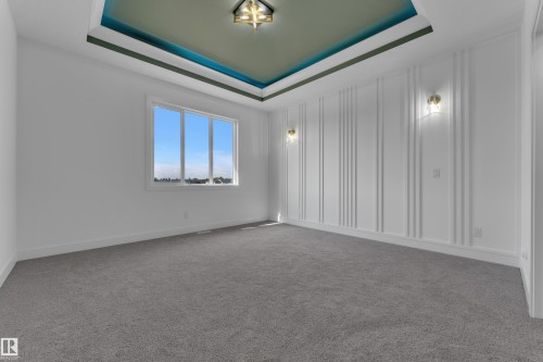 Tray ceiling with accent paint, recessed lighting fixture, wall paneling, and two sconce lights - 4212 63 Street, Beaumont, AB 