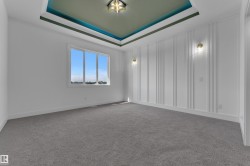 Tray ceiling with accent paint, recessed lighting fixture, wall paneling, and two sconce lights - 