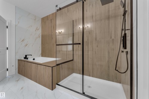 Modern bathroom with a soaker tub, black matte fixtures, glass-enclosed shower, wood-look tile accents, and white marble-look floor and wall tile - 4212 63 Street, Beaumont, AB 