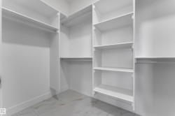 Built-in closet system with multiple shelving units and hanging rods, complemented by white walls and tile flooring - 