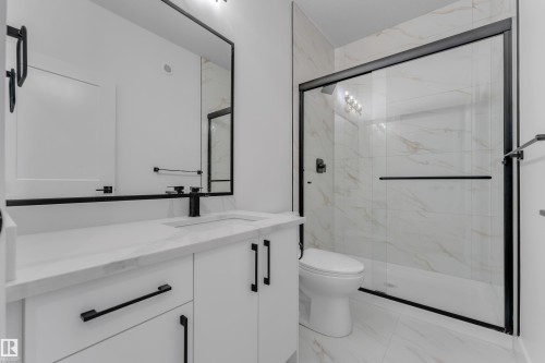 White vanity with integrated sink, black fixtures, and a framed mirror - 4212 63 Street, Beaumont, AB 