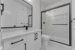 White vanity with integrated sink, black fixtures, and a framed mirror - 
