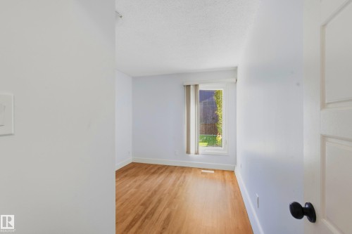 Light wood-finish flooring, white walls, and a large window with vertical blinds - 258 Surrey Gardens Nw, Edmonton, AB 