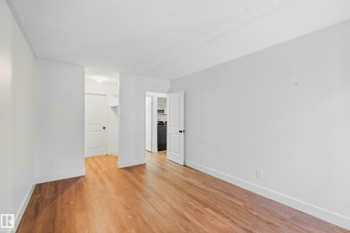 Bright interior space featuring wood-finish flooring, white walls, and white trim - 258 Surrey Gardens Nw, Edmonton, AB 