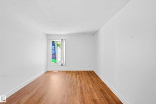 Wood-finish flooring with white baseboards, bright white walls, and a window with white trim - 258 Surrey Gardens Nw, Edmonton, AB 