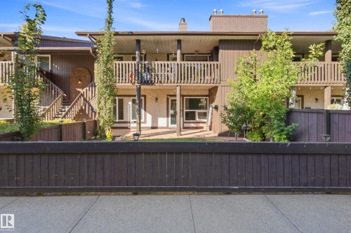 Two-story exterior with wood siding, multiple balconies with wood railings, a private entrance with wood stairs, and a secure wood fence - 258 Surrey Gardens Nw, Edmonton, AB 