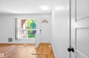 Wood-finish flooring throughout, white interior door, and a front entry door with an arched window - 258 Surrey Gardens Nw, Edmonton, AB 