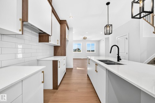 Modern kitchen featuring a dual-basin sink with a matte black faucet, white countertops, and wood-finish cabinetry - 9 Tilia Place, Spruce Grove, AB 