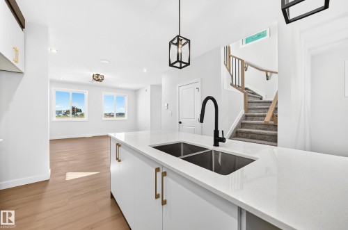 Kitchen island with a dual basin sink, black gooseneck faucet, and white countertop - 9 Tilia Place, Spruce Grove, AB 