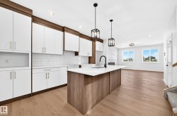 Open-concept kitchen featuring an island with a built-in sink, white cabinetry with wood-finish accents, and a tile backsplash - 