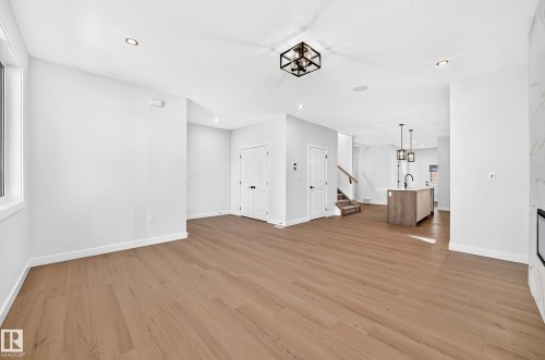 Open-concept living space featuring wood-finish flooring, recessed lighting, and a modern kitchen island with pendant lighting - 9 Tilia Place, Spruce Grove, AB 