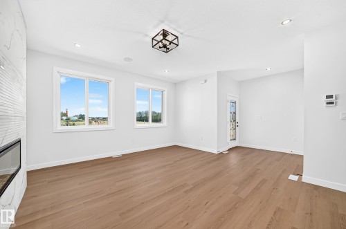 Light wood-finish flooring, recessed lighting, and a modern ceiling light fixture - 9 Tilia Place, Spruce Grove, AB 