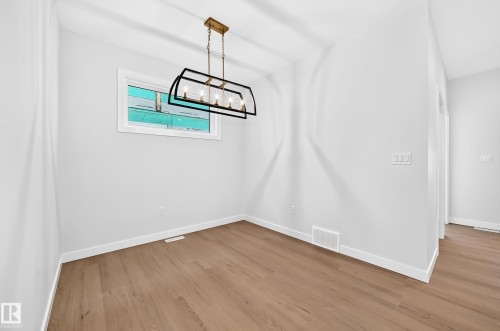 Wood-finish flooring, white walls, and a modern rectangular chandelier with a gold-tone chain - 9 Tilia Place, Spruce Grove, AB 
