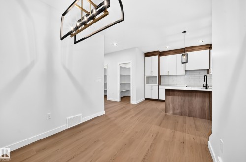 Open-concept floorplan featuring wood-finish flooring, a modern chandelier, and recessed lighting - 9 Tilia Place, Spruce Grove, AB 