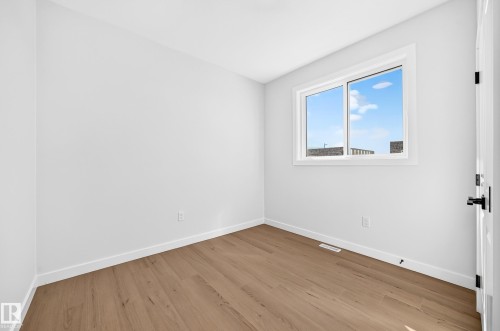 Neutral-toned walls, wood-finish flooring, white window trim, and a black door handle - 9 Tilia Place, Spruce Grove, AB 