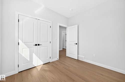 Wood-finish flooring throughout, white walls, white trim, and white doors with matte black hardware - 9 Tilia Place, Spruce Grove, AB 