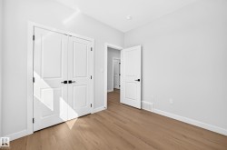 Wood-finish flooring throughout, white walls, white trim, and white doors with matte black hardware - 