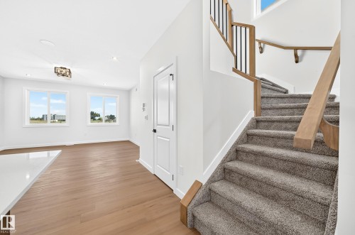 Carpeted staircase with wood-finish handrail and black metal balusters - 9 Tilia Place, Spruce Grove, AB 