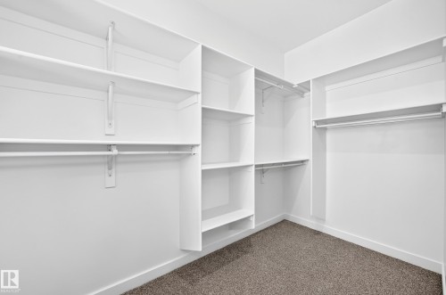 White built-in shelving, multiple hanging rods, and dark carpeting - 9 Tilia Place, Spruce Grove, AB 
