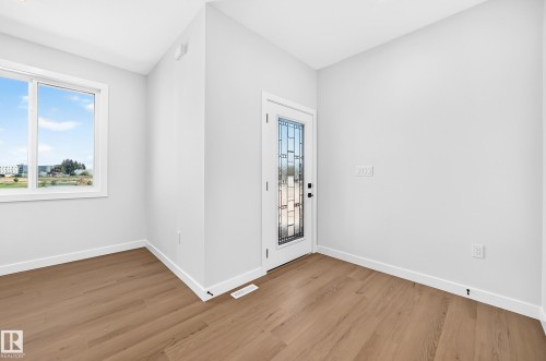 Entryway featuring wood-finish flooring, white walls, a window, and a door with decorative glass panels - 9 Tilia Place, Spruce Grove, AB 